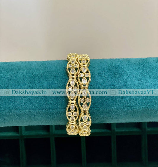 Gold bracelet with intricate design on a teal cushion