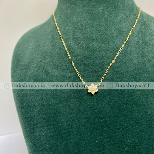 Gold necklace with a flower pendant on a green mannequin