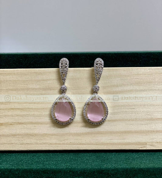 Pair of earrings with pink gemstones on a wooden surface