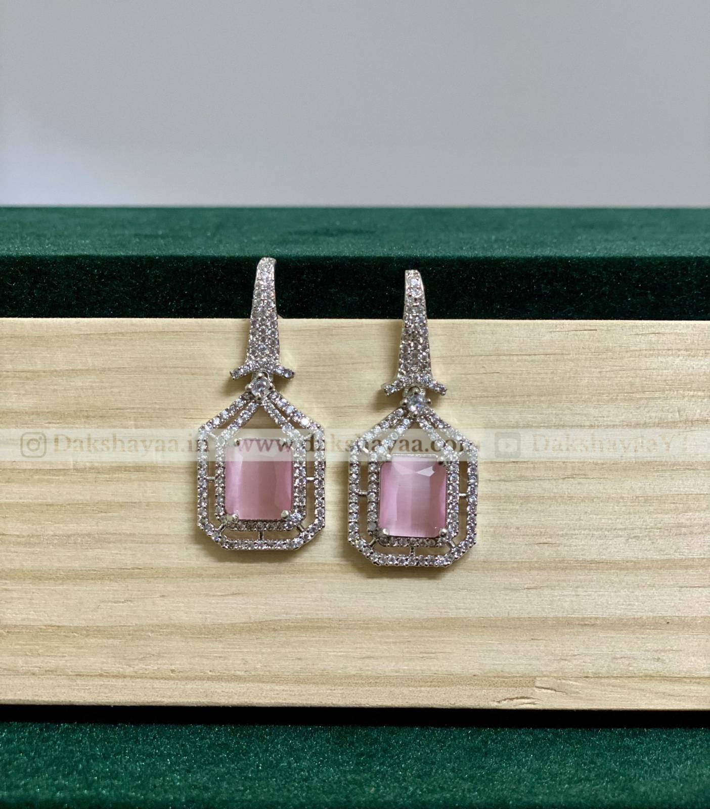 Pair of earrings with pink gemstones on a wooden surface