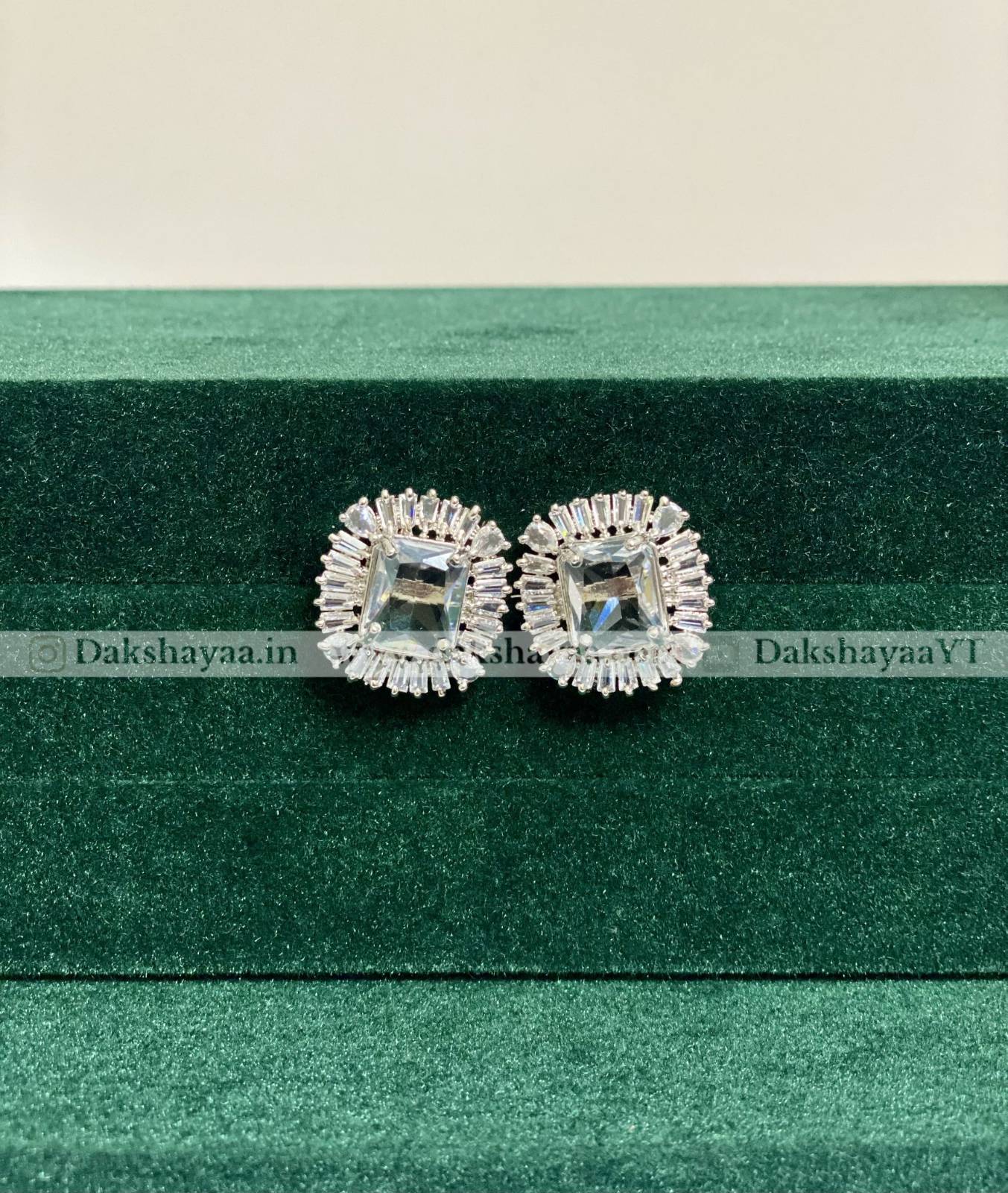 Pair of silver earrings on a green striped background