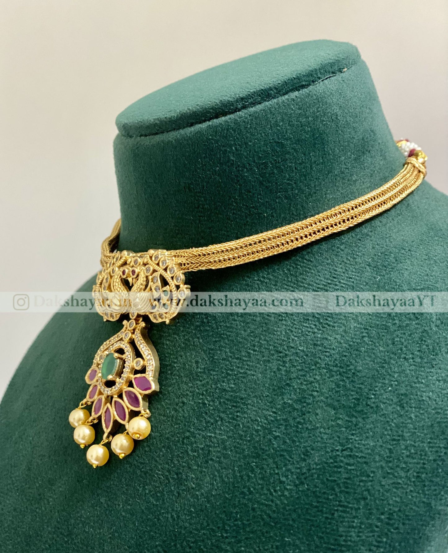 Gold necklace with pendant on a green velvet stand