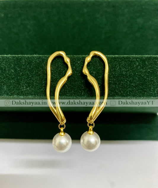 Gold earrings with pearl drops on a green background