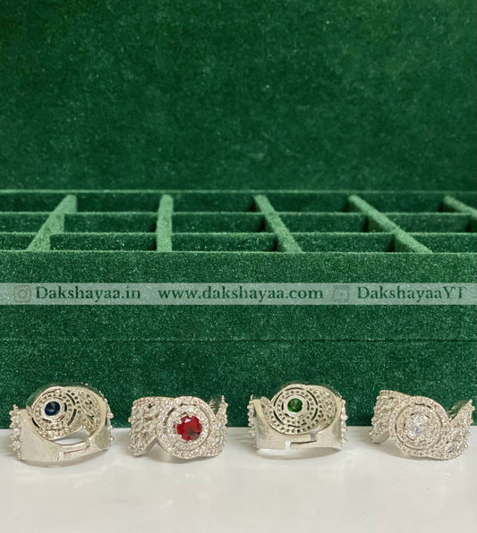 Four silver rings with gemstones on a green velvet background