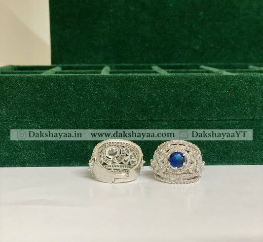 Silver rings with a blue gemstone on a white surface with a green box in the background.