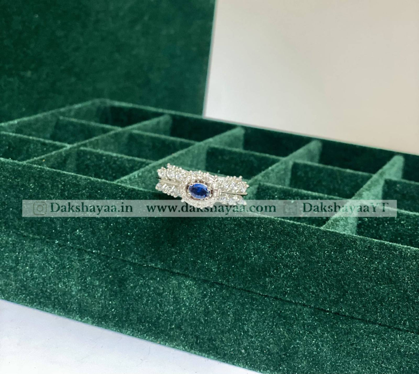 Silver ring with a blue gemstone on a green jewelry box