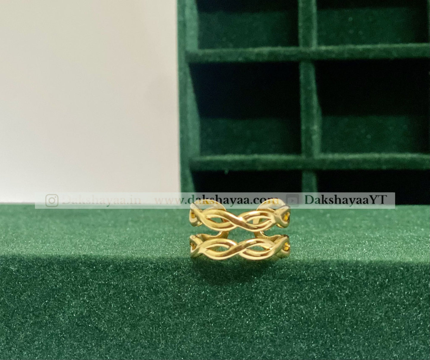 Gold ring with a decorative design on a green textured surface
