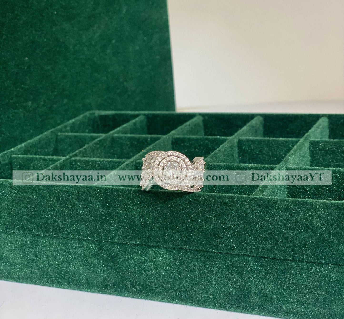 Silver ring on a green jewelry box with visible branding.