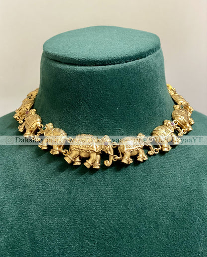 Gold elephant necklace on a green velvet stand