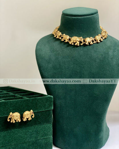 Gold elephant-themed jewelry set on a green velvet stand with a matching box.