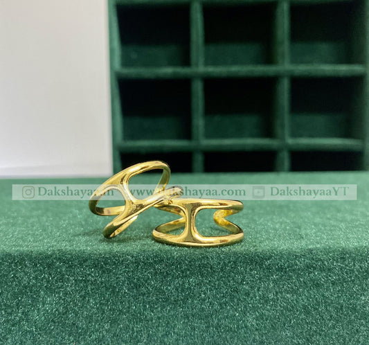 Two gold rings on a green surface with a green jewelry box in the background.