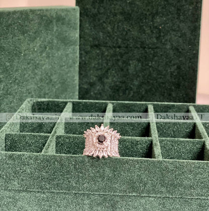 Silver ring with a central black gemstone on a green jewelry display box.