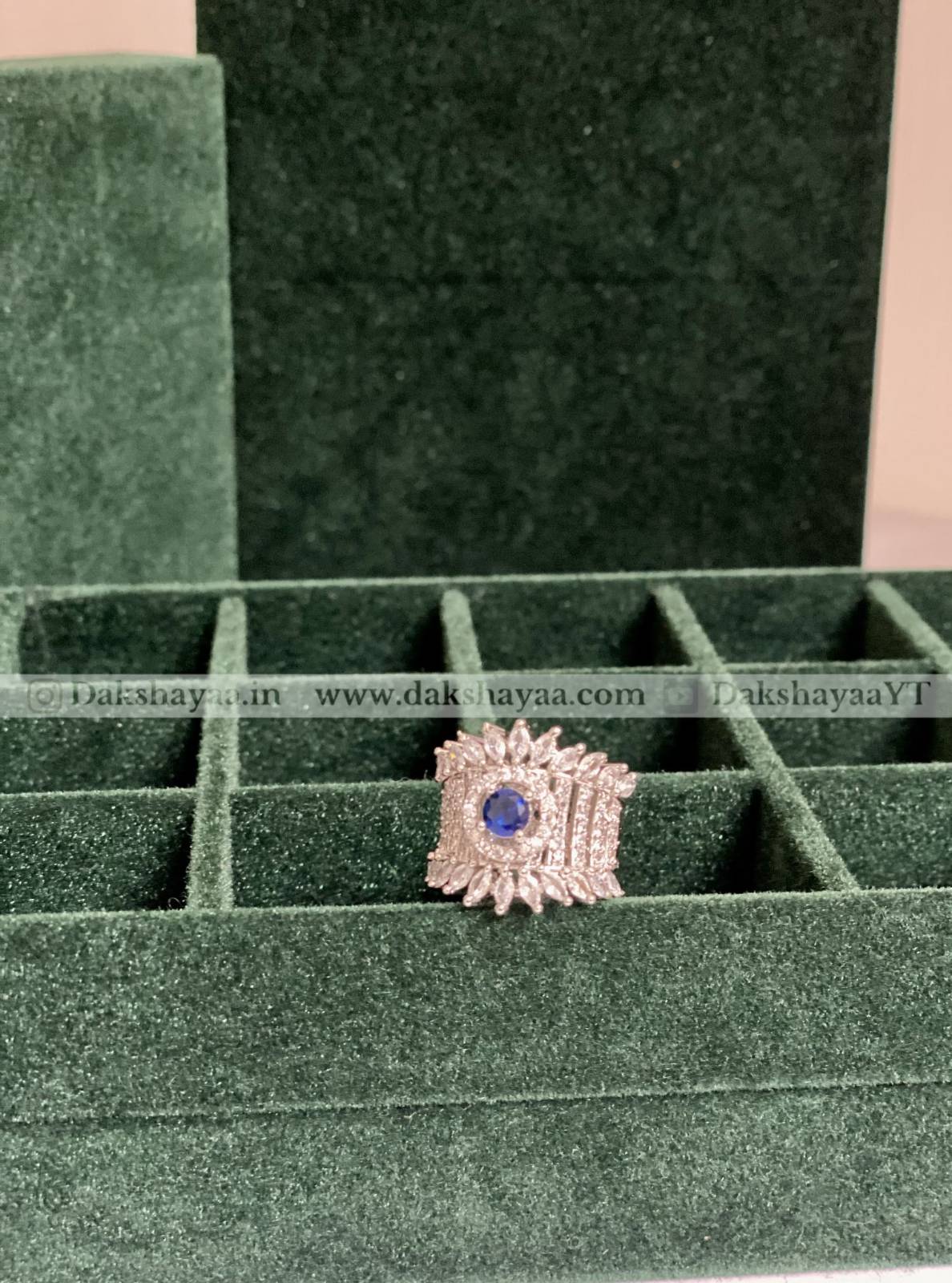 Jewelry ring with a blue gemstone on a green velvet display box.