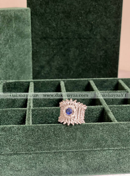 Jewelry ring with a blue gemstone on a green velvet display box.