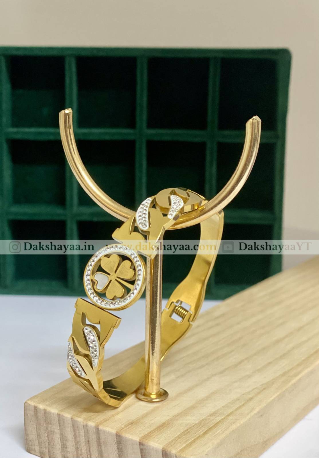 Gold kada stand with clover design on a wooden block against a green grid background