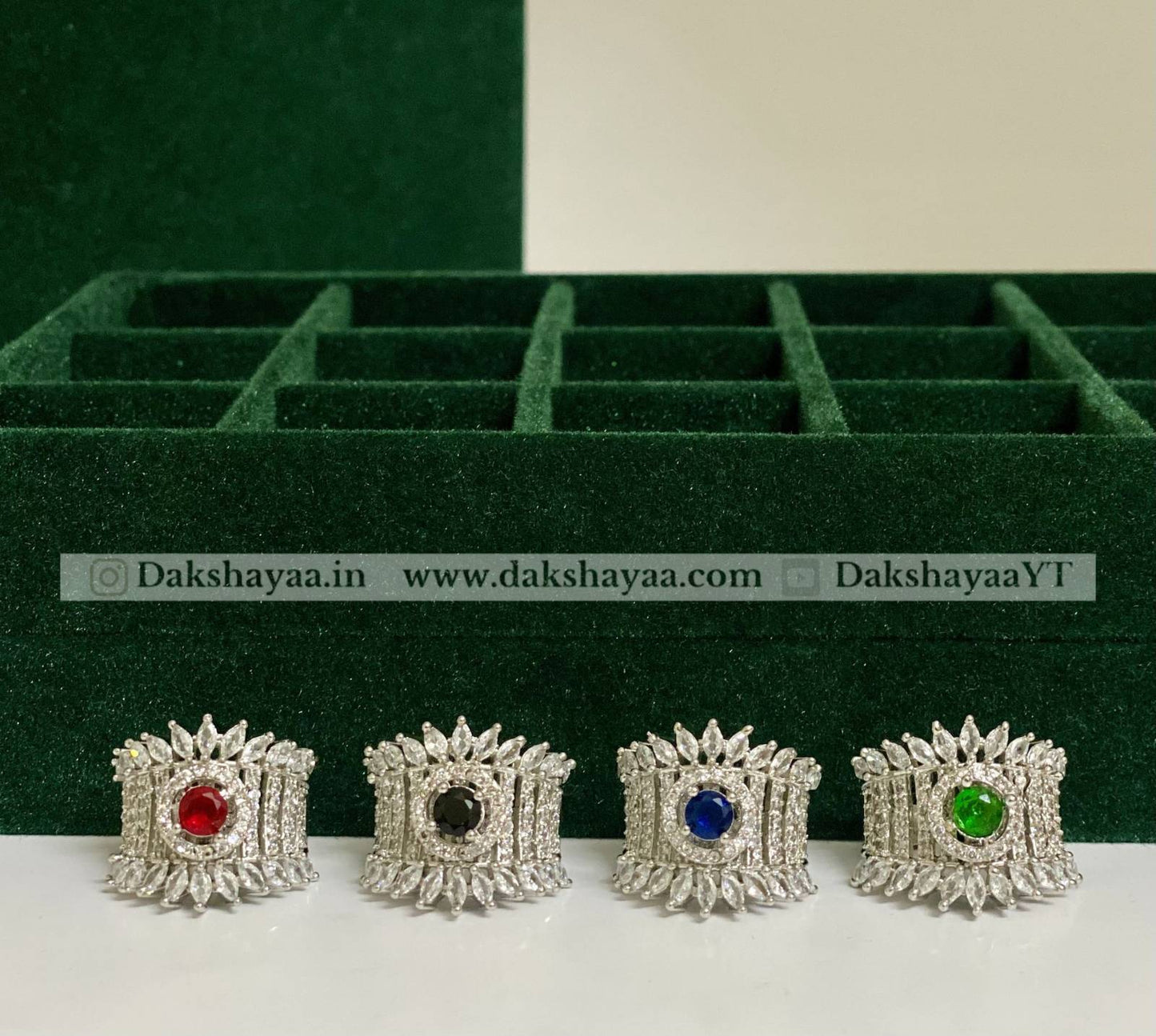 Set of silver rings with colored gemstones on a green display box.