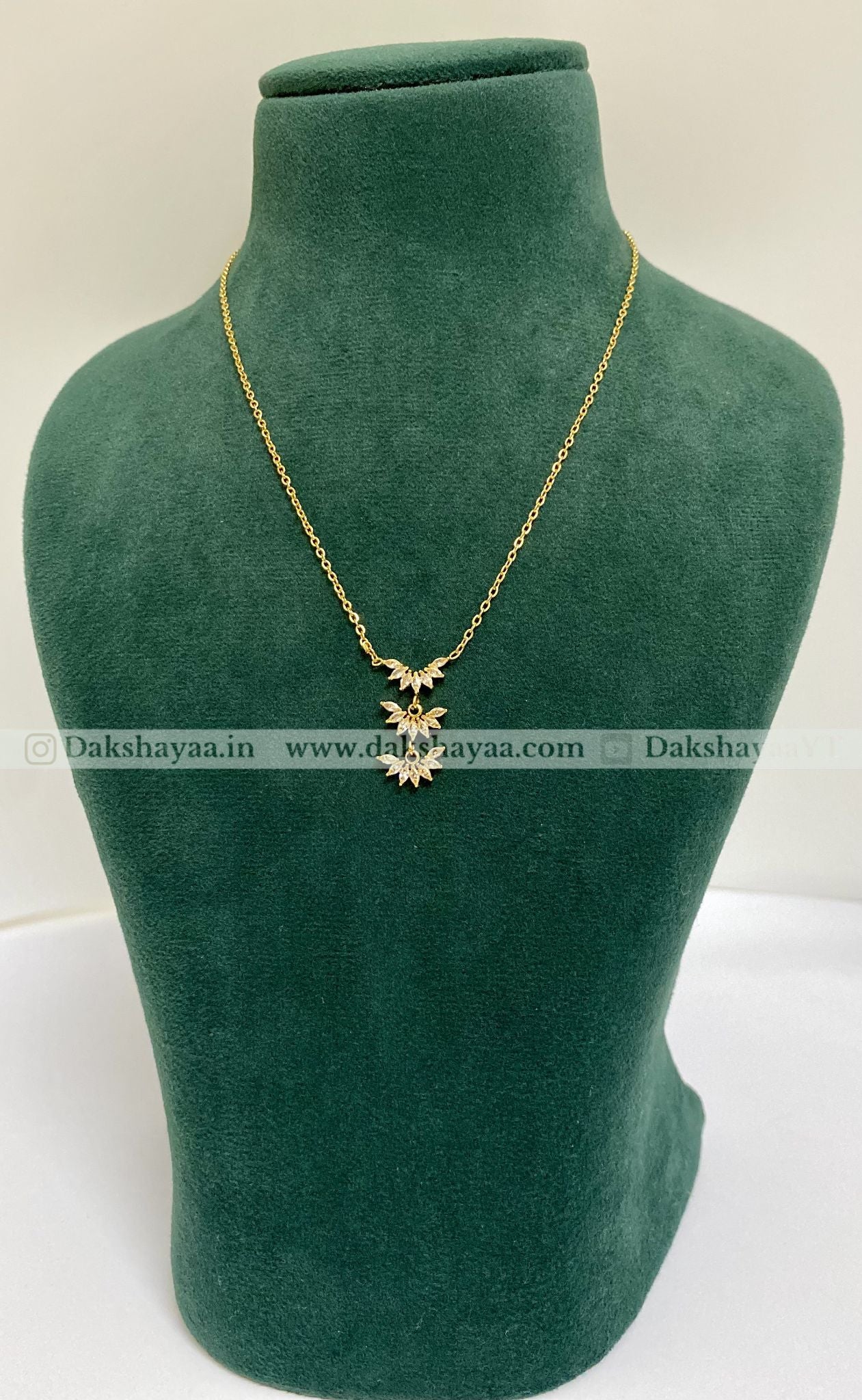 Gold necklace with a pendant on a green mannequin bust.
