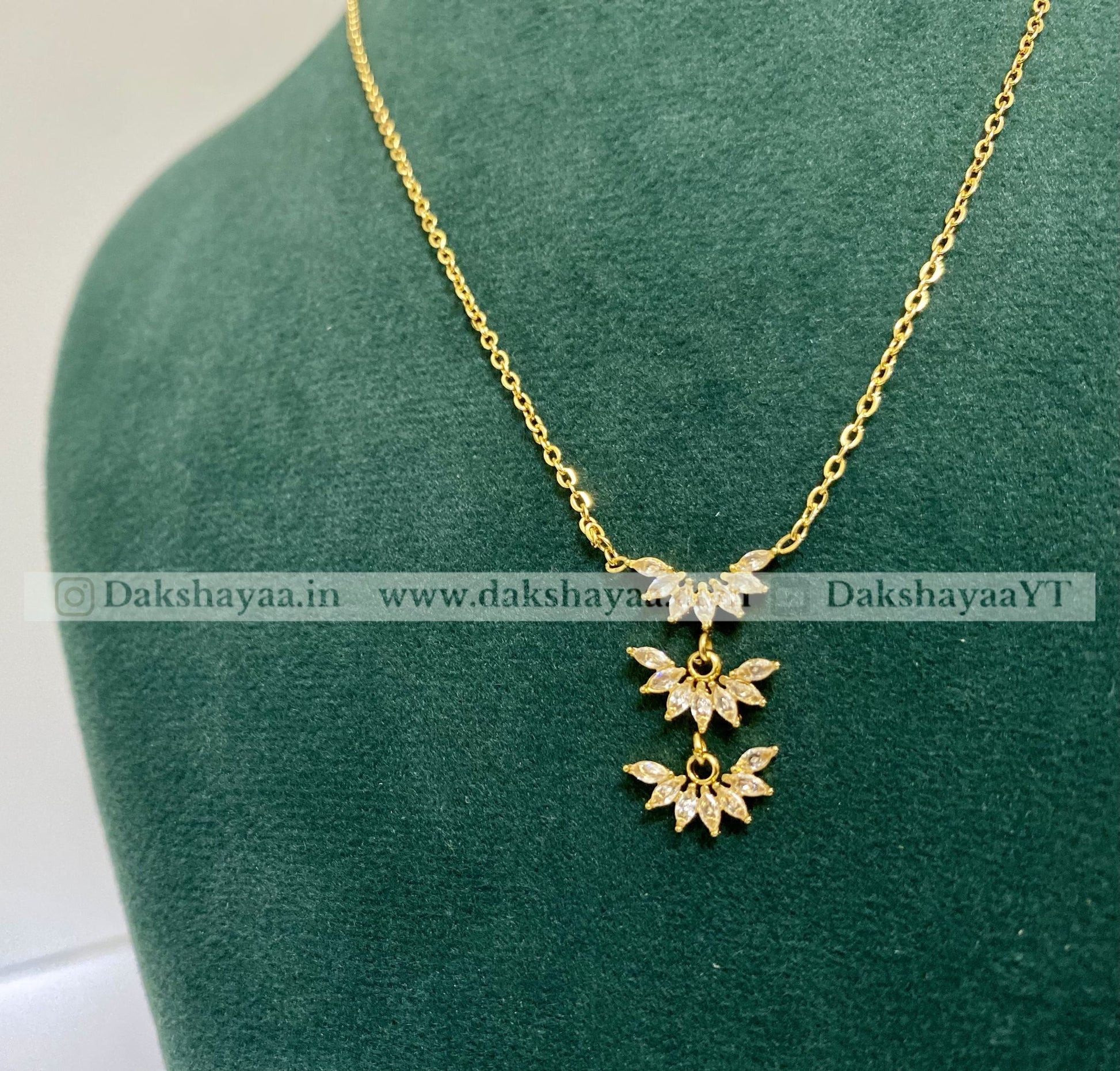 Gold necklace with floral pendants on a green mannequin