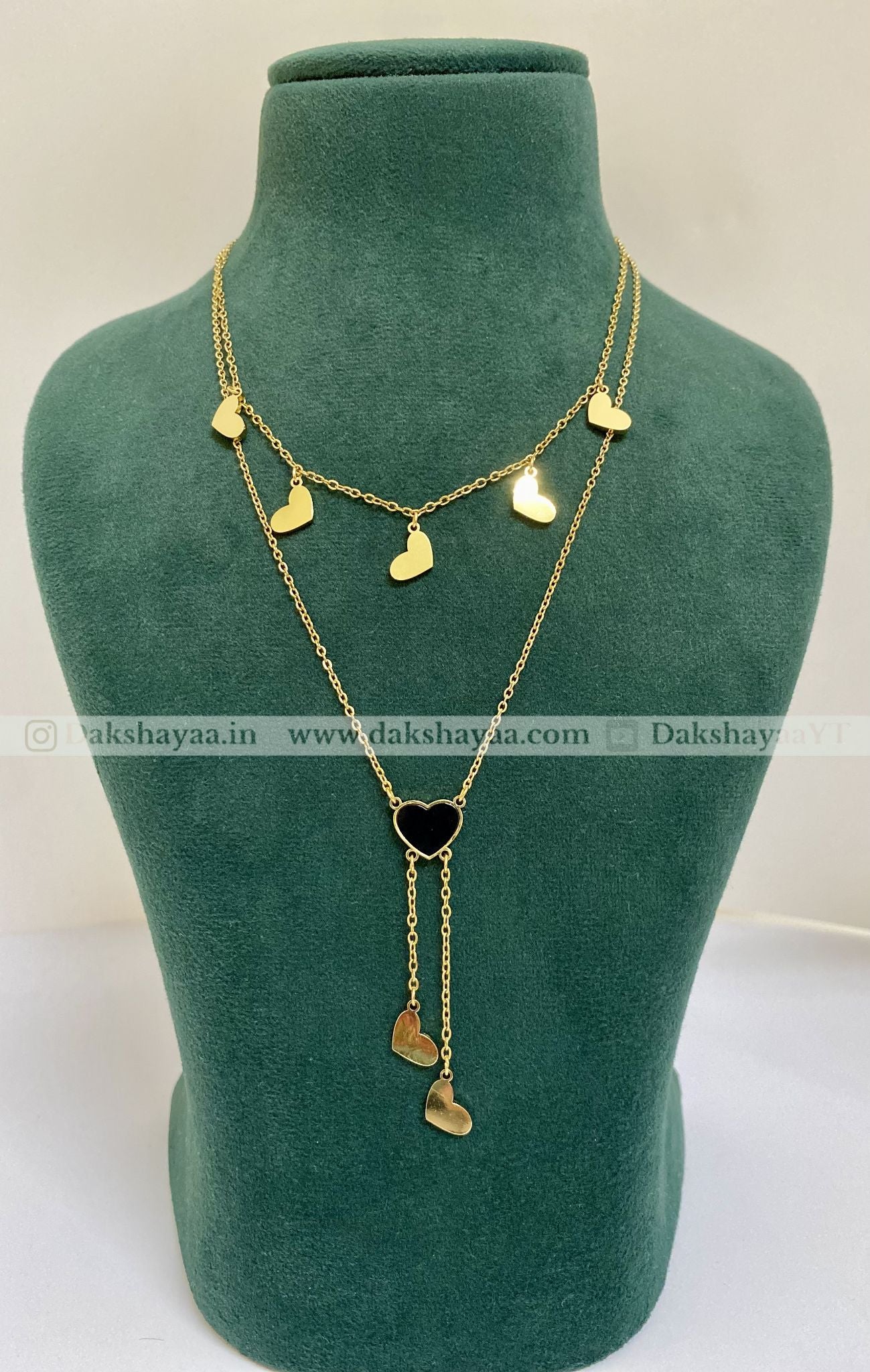 Gold necklace with heart pendants on a green mannequin bust.