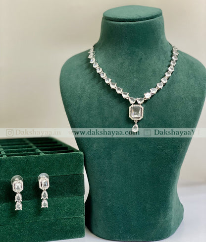 Jewelry set with necklace and earrings on a green mannequin and box, brand 'Dakshayaa' visible.