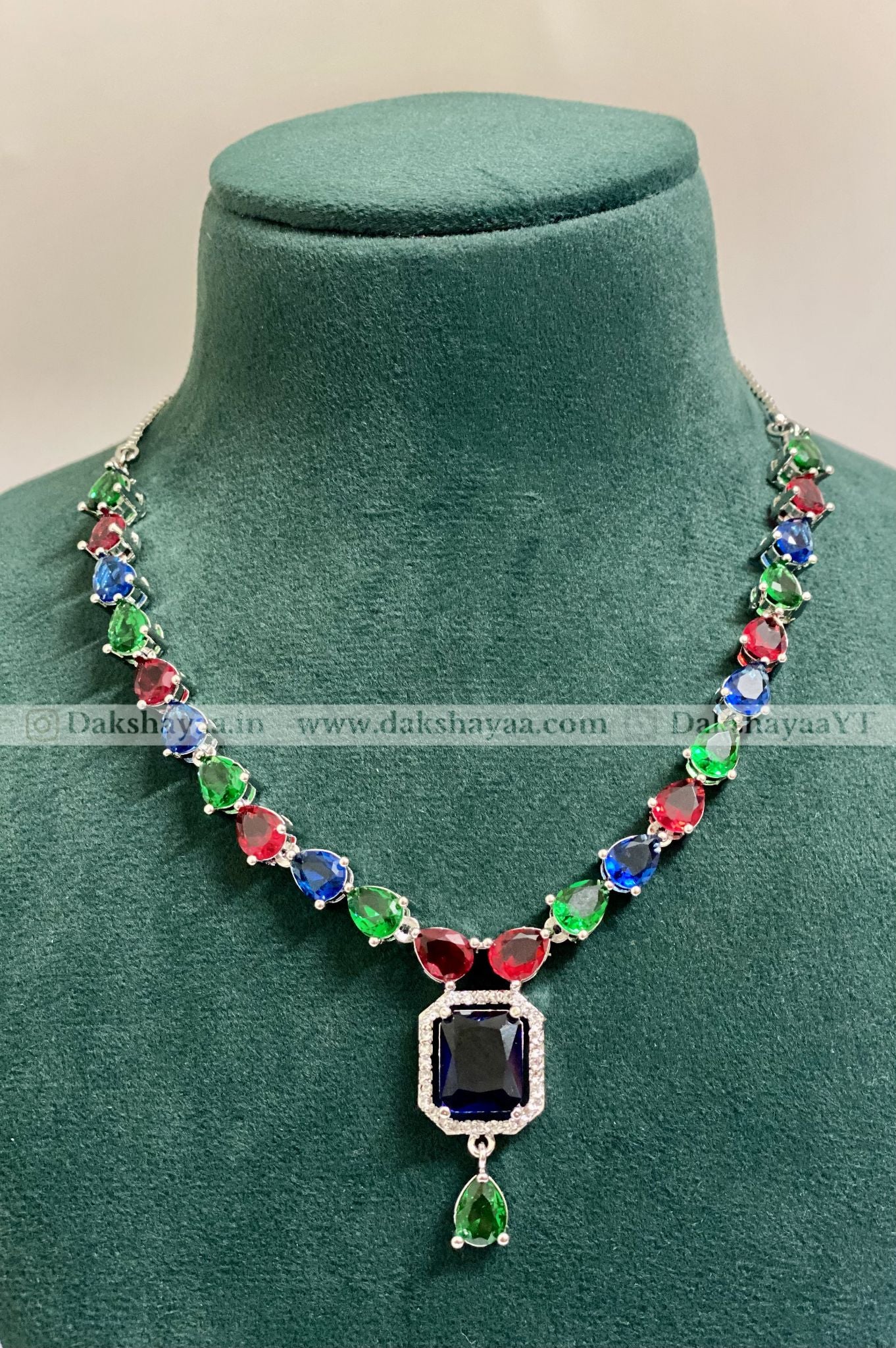 Colorful beaded necklace with a central gemstone on a green mannequin.