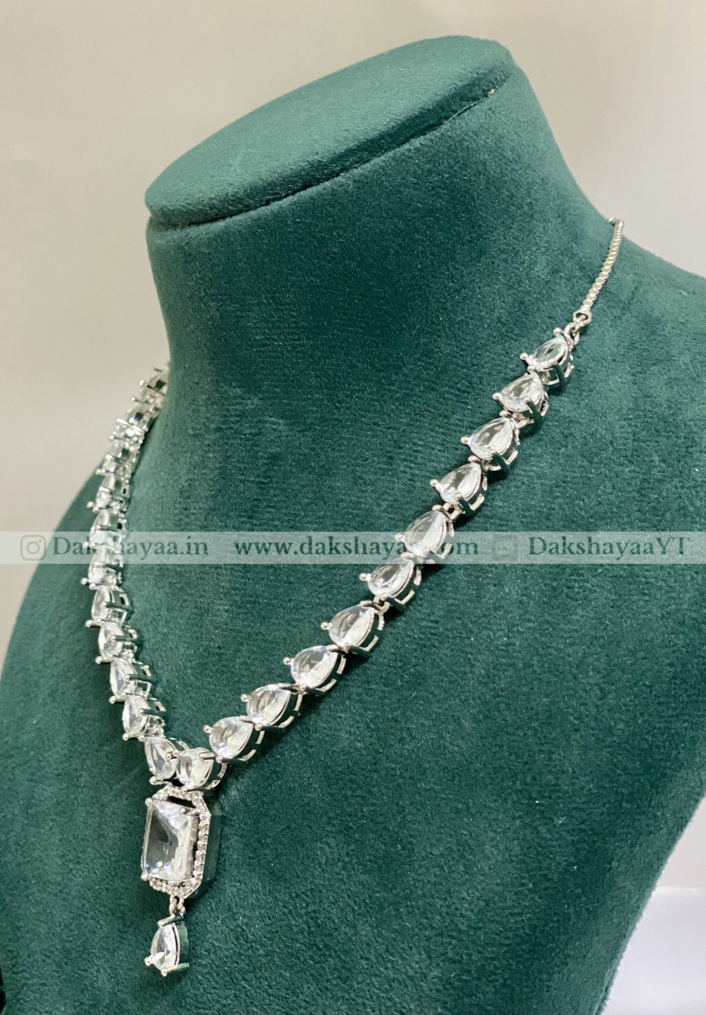 Silver necklace with clear stones on a green mannequin bust