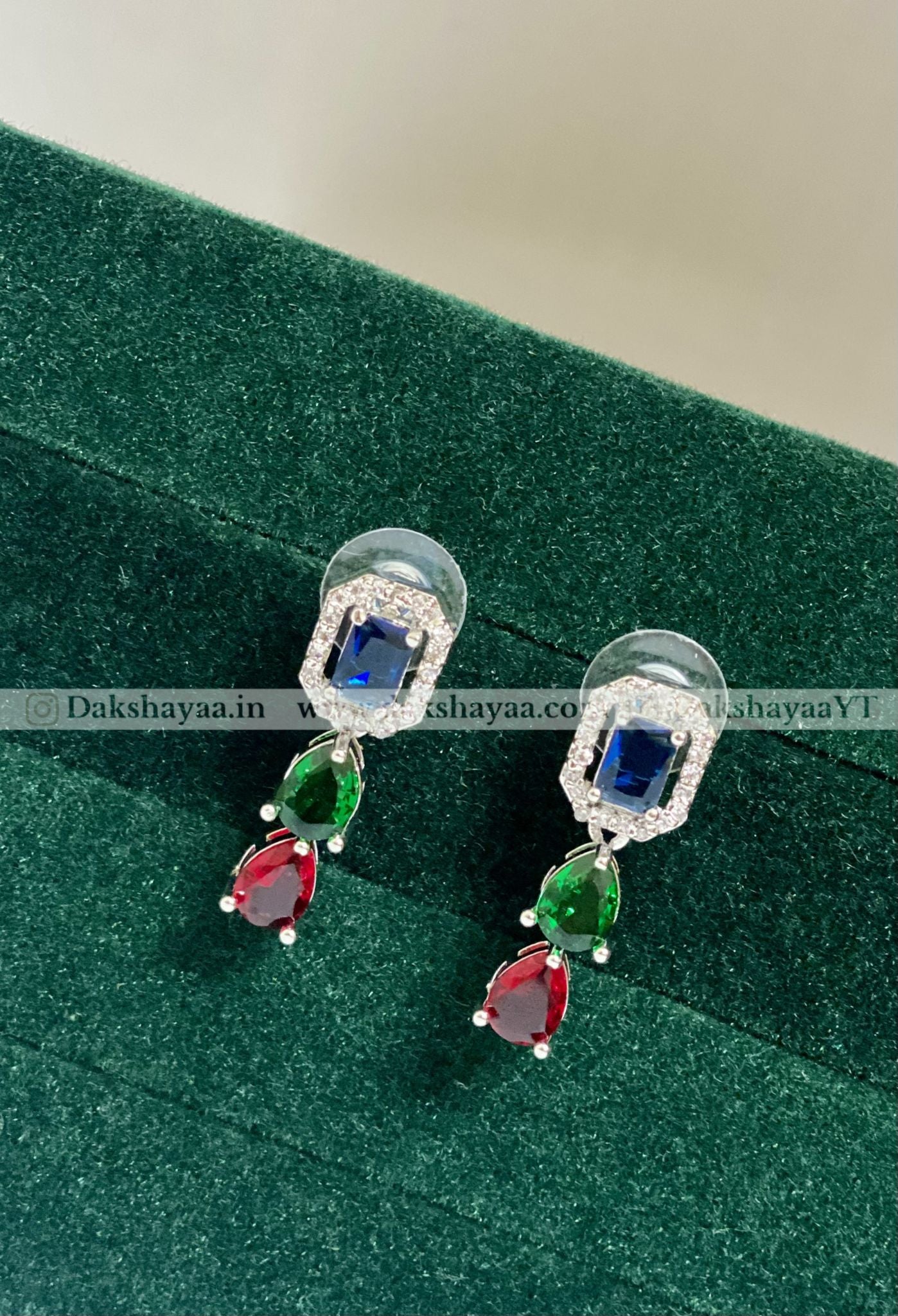 Pair of earrings with gemstones on a green surface