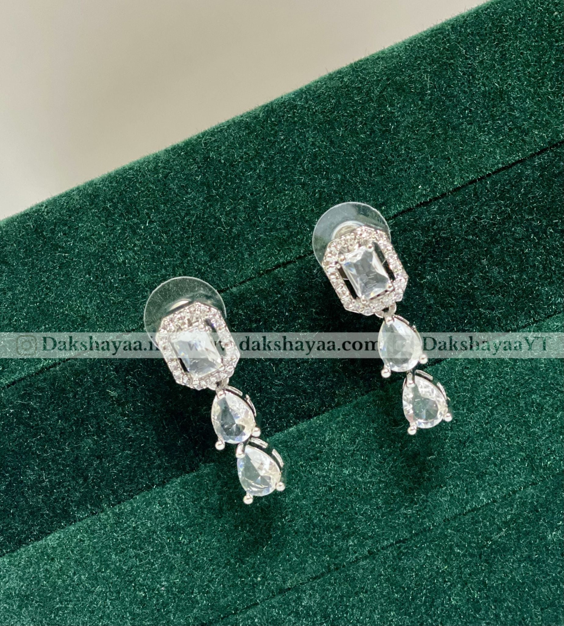 Pair of silver earrings with gemstones on a green velvet background