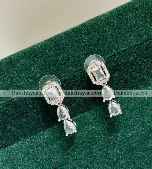 Pair of silver earrings with gemstones on a green velvet background