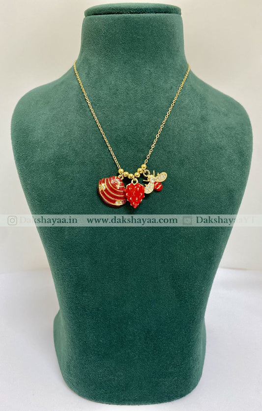 Gold necklace with red and gold pendants on a green mannequin bust.