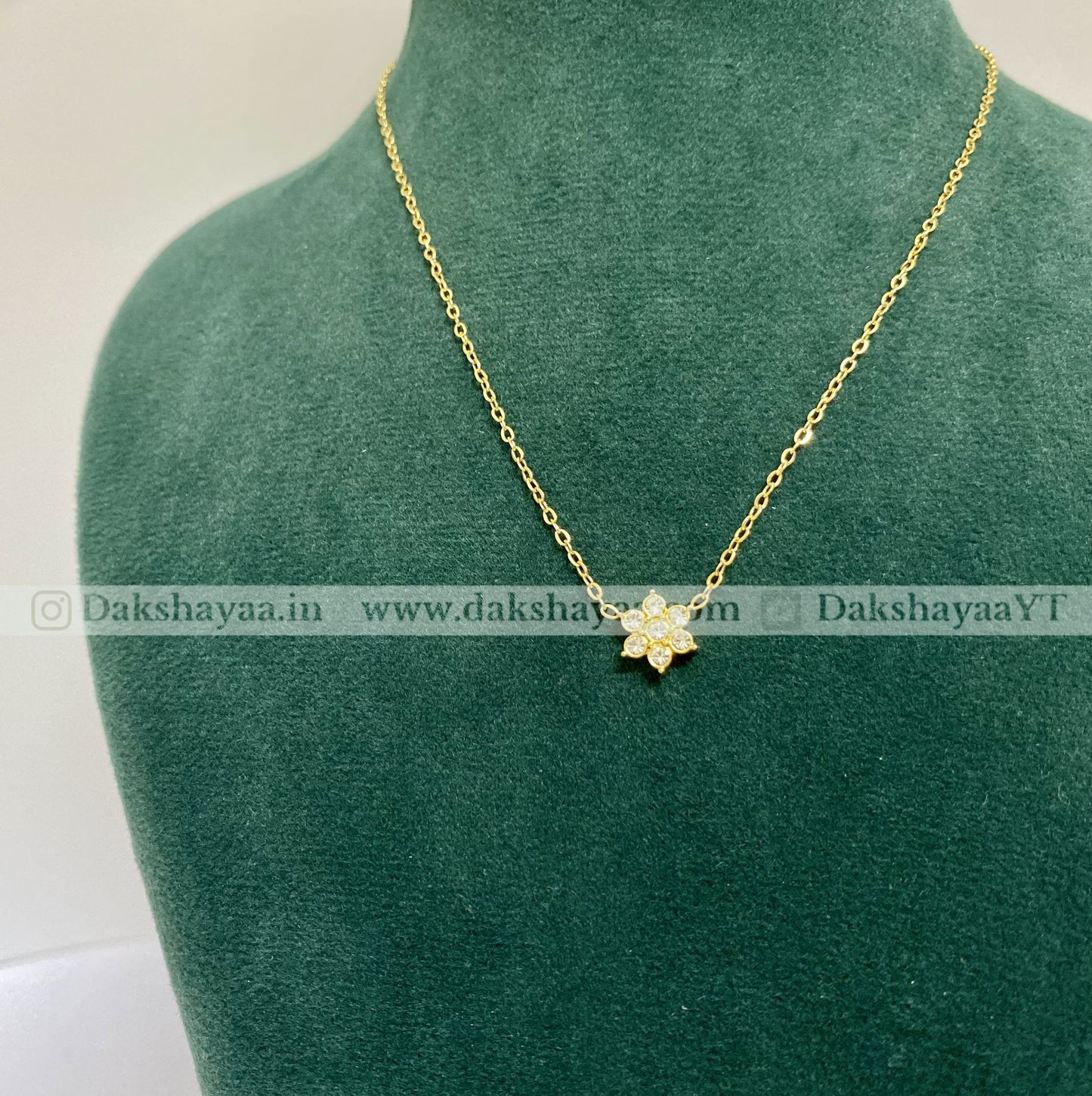 Gold necklace with a flower pendant on a green mannequin