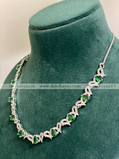 Silver necklace with green gemstones on a green velvet stand