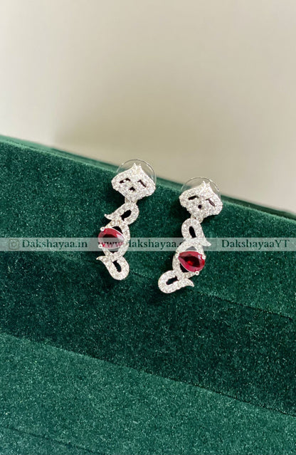 Silver earrings with red gemstones on a green cushion
