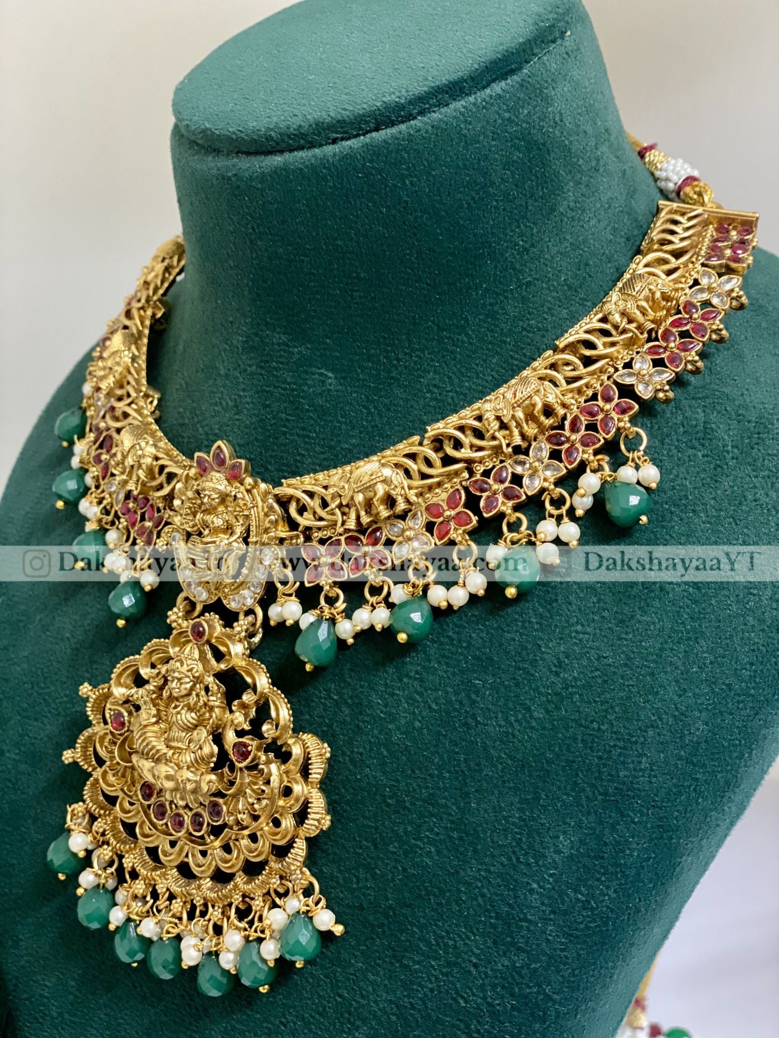Gold necklace with green beads on a green mannequin bust