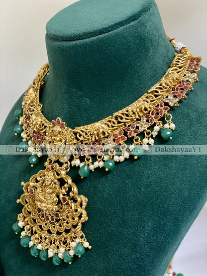 Gold necklace with green beads on a green mannequin bust