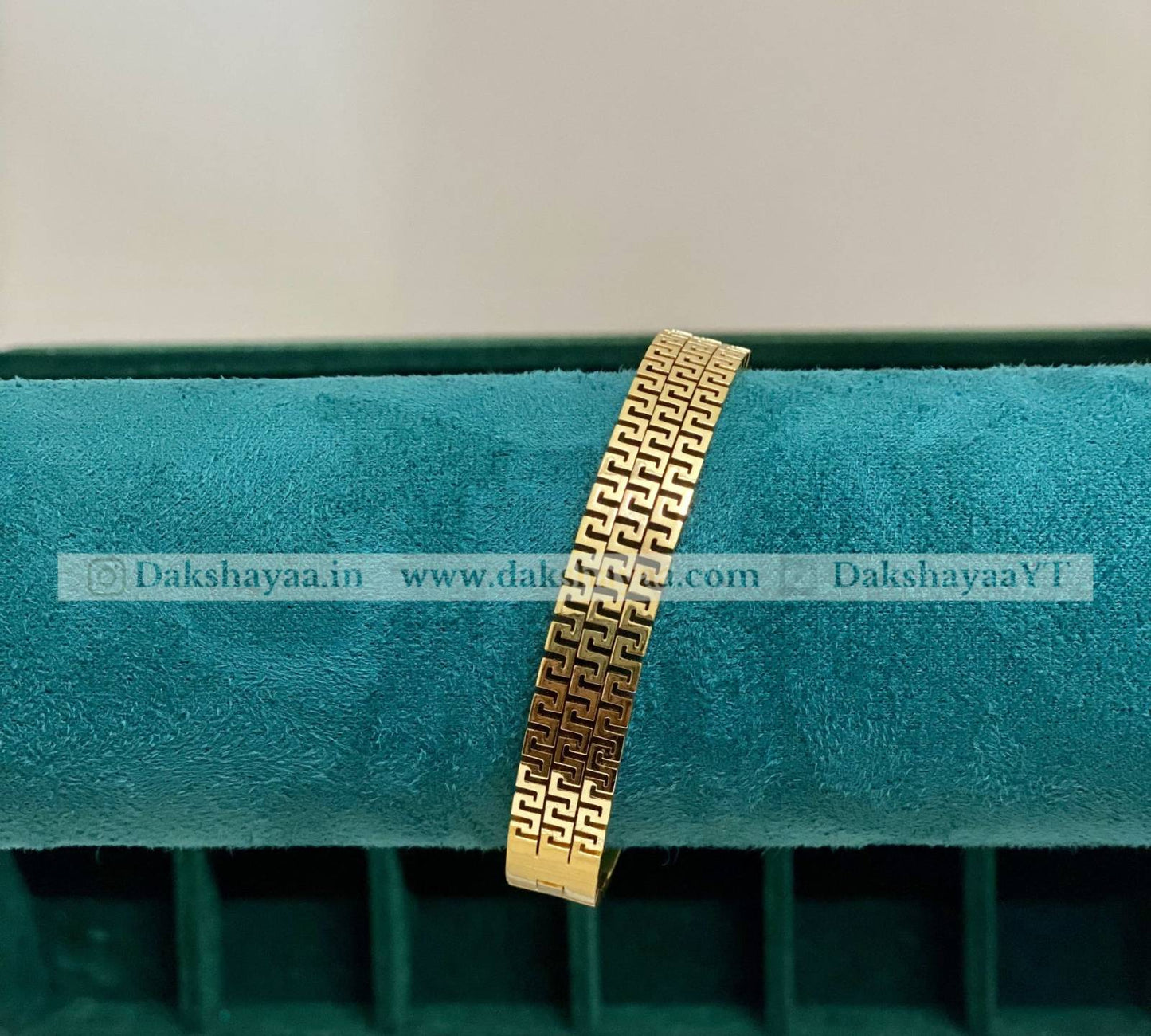 Gold bracelet on a green cushion with visible branding