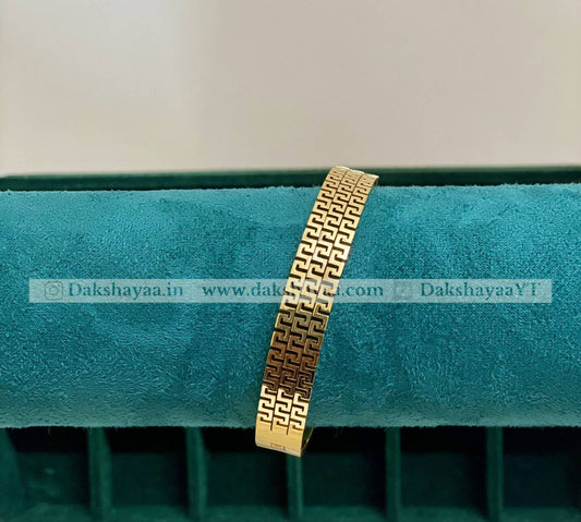 Gold bracelet on a green cushion with visible branding