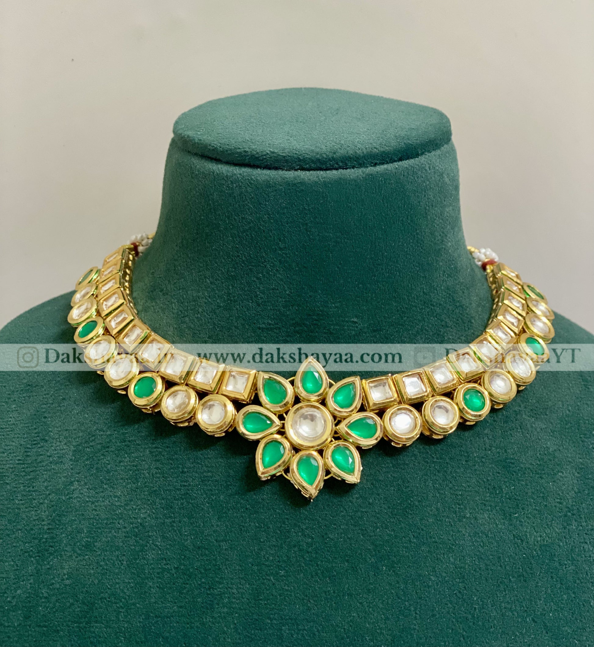 Decorative necklace with green and white stones on a green velvet stand