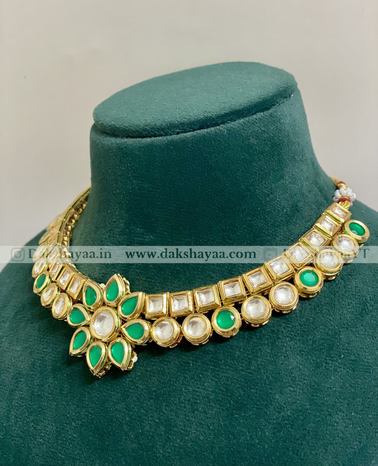 Decorative necklace with green and white stones on a green velvet stand