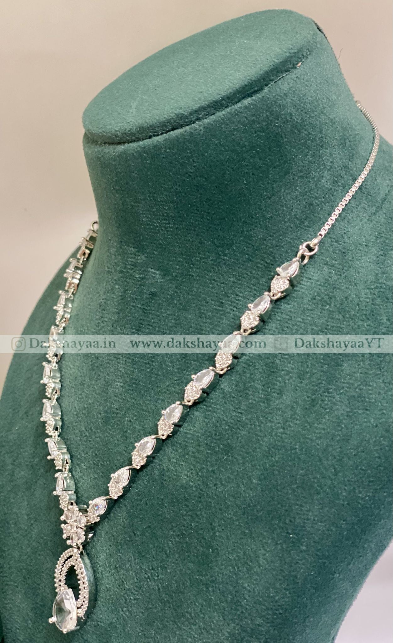 Silver necklace on a green velvet mannequin