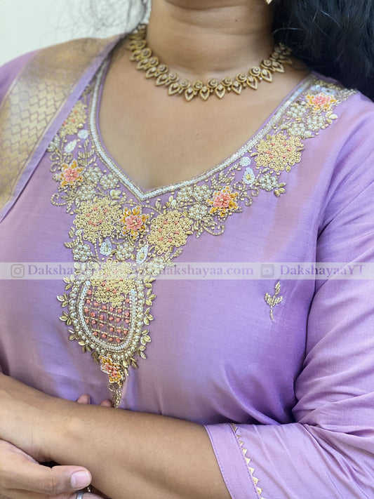 Purple outfit with intricate gold embroidery and a necklace.