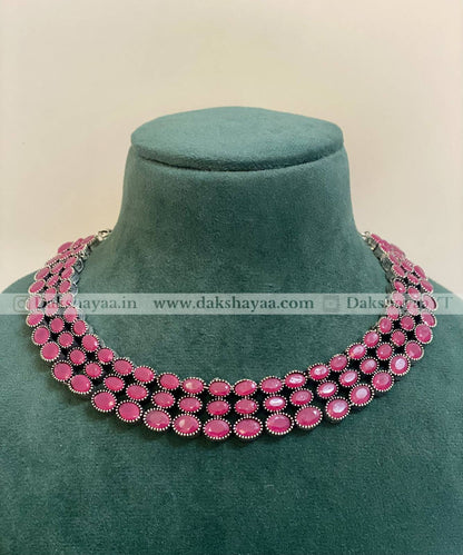 Pink beaded necklace on a green mannequin against a beige background