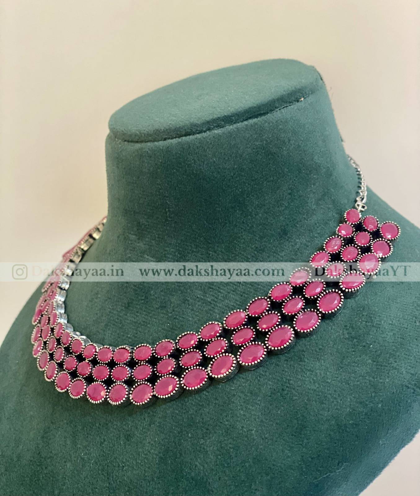 Necklace with pink stones on a green velvet stand