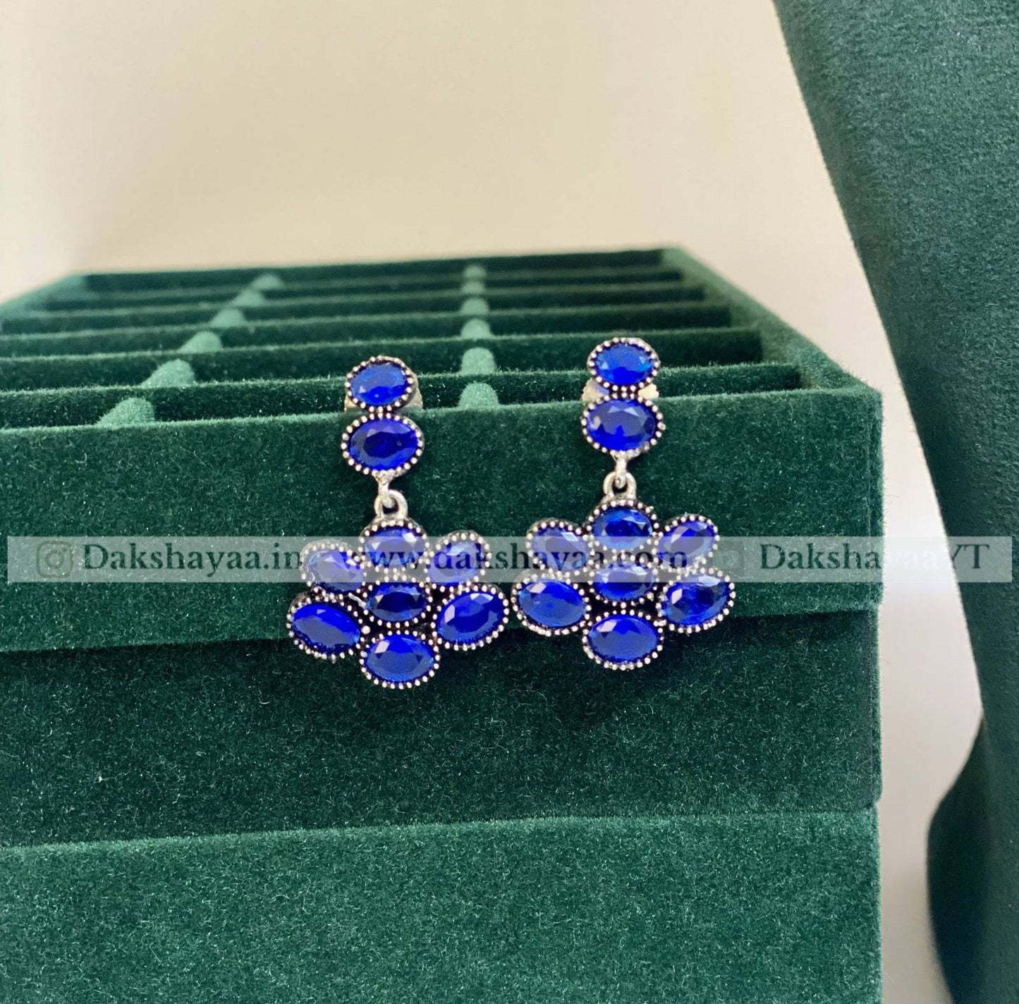 Blue gemstone earrings on a green jewelry display box