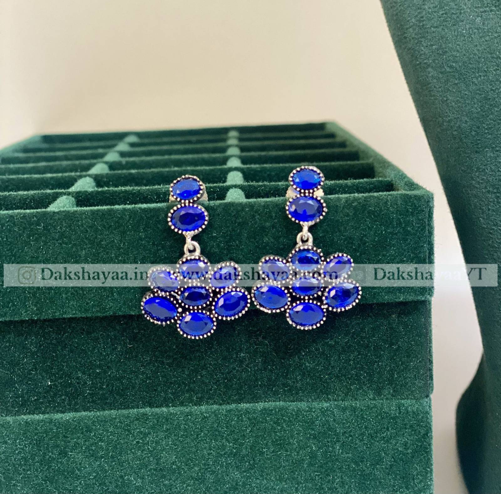 Blue gemstone earrings on a green jewelry display box