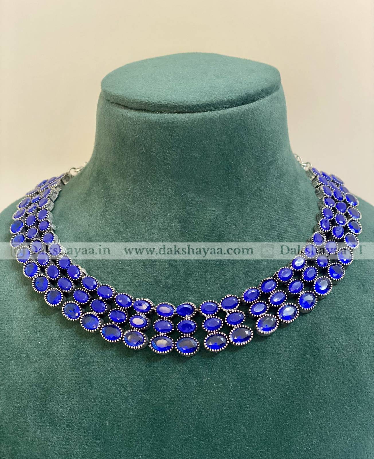 Blue gemstone necklace on a green velvet mannequin bust