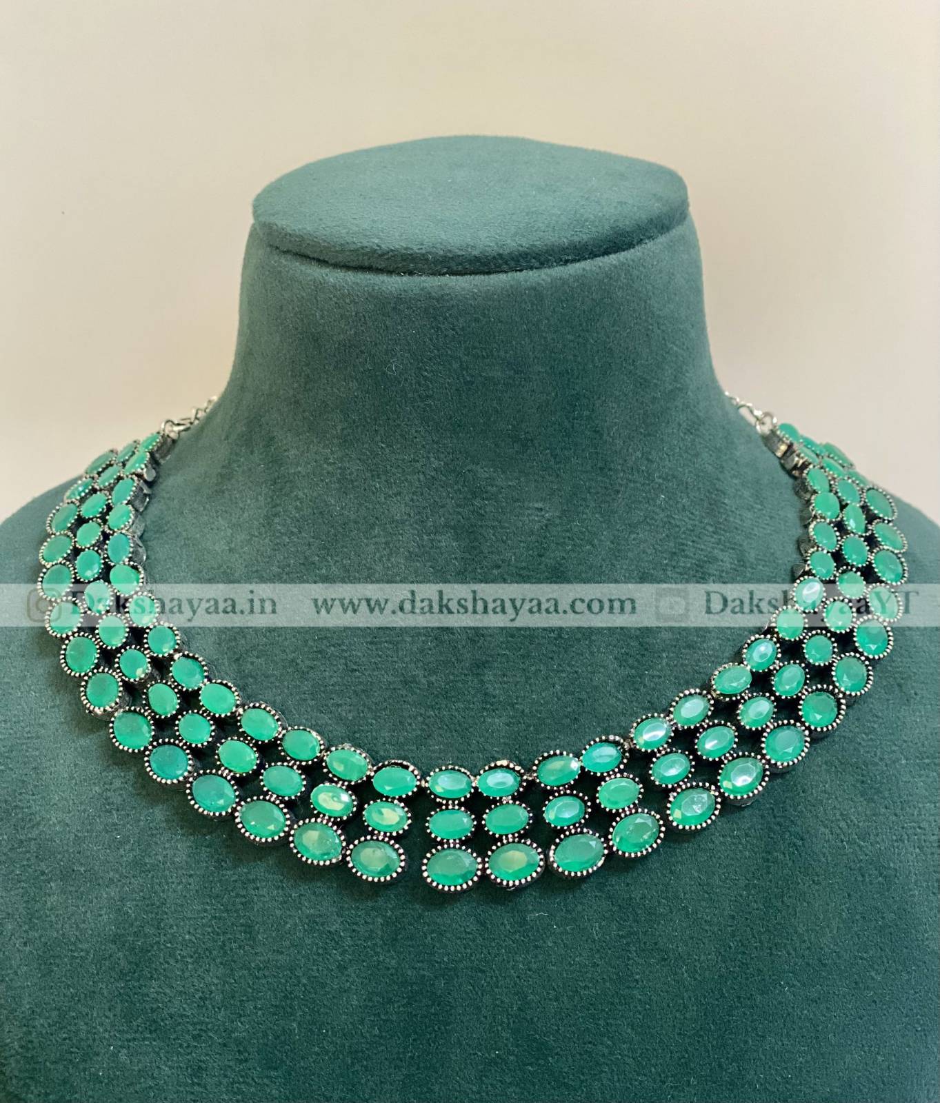 Turquoise necklace on a green mannequin bust with 'Dakshayaa' branding.