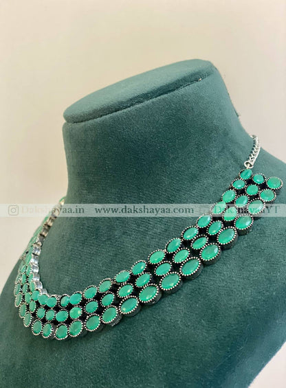Green beaded necklace on a green velvet stand with a beige background