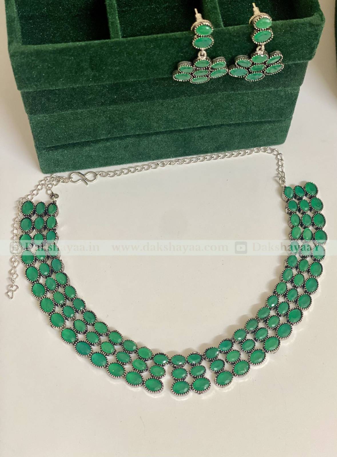 Green necklace and earrings set on a white background with a green jewelry box.