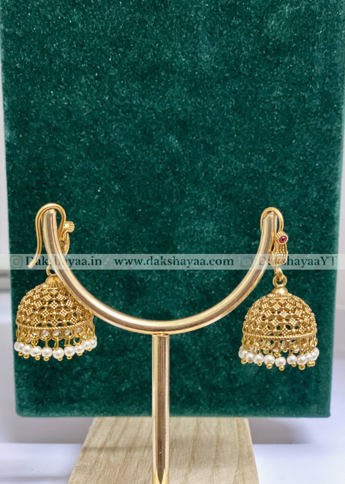 Gold earrings with pearl details on a green stand